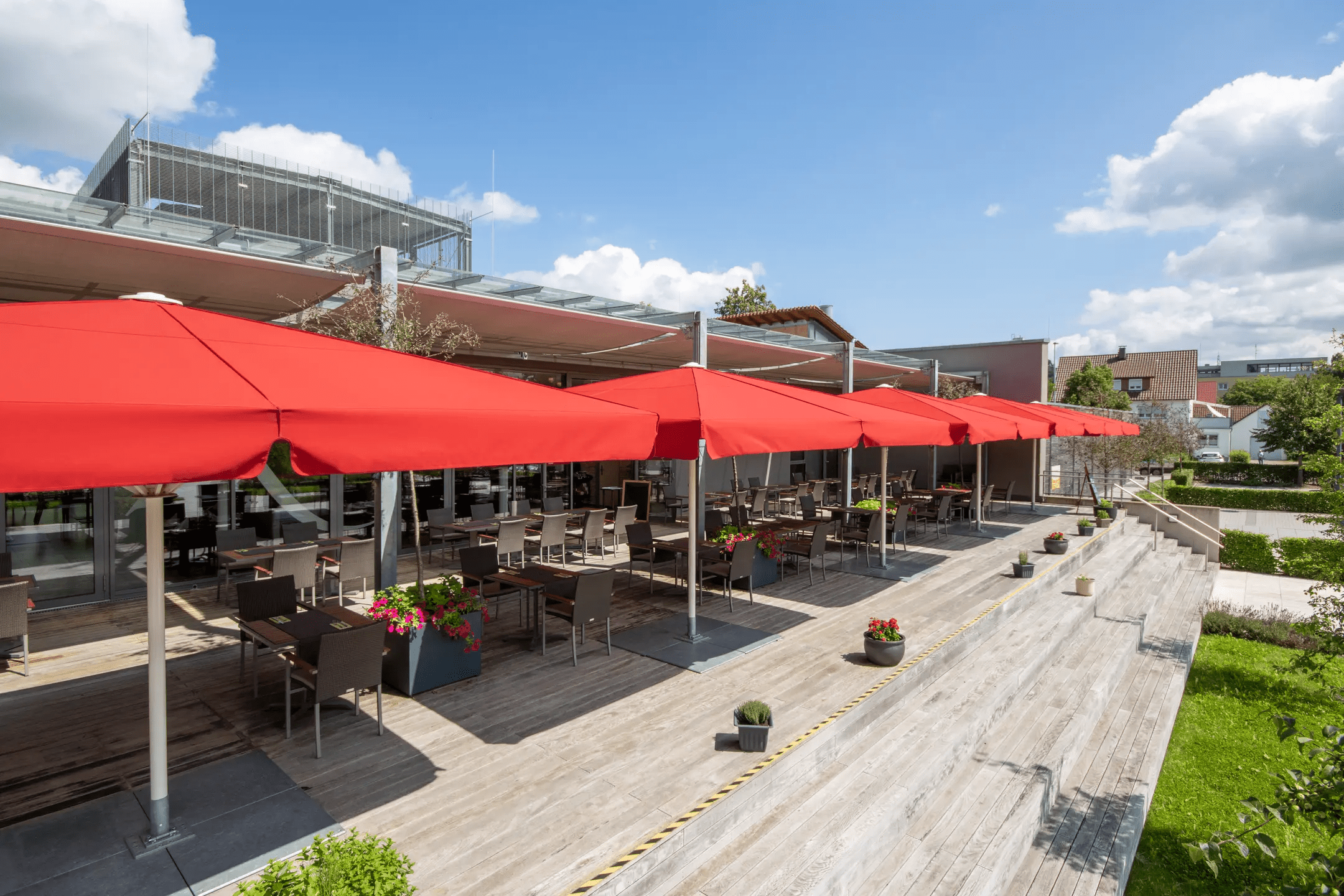 Five red Schattello parasols on a patio area