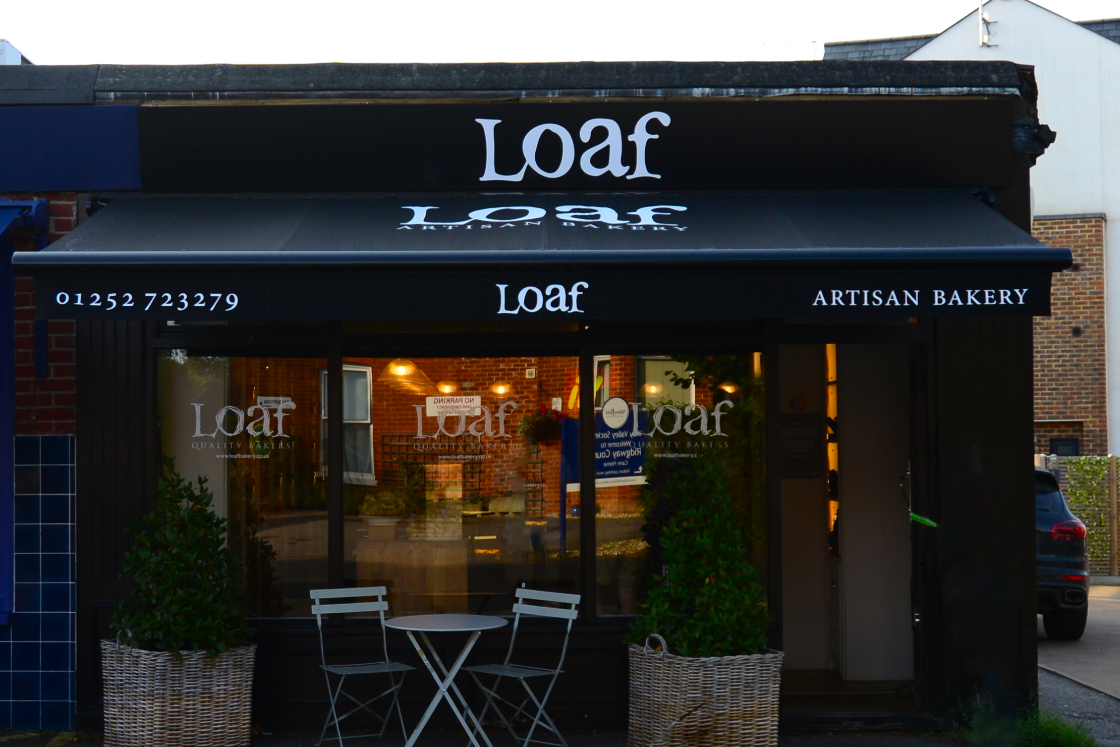 Black branded awning for a bakery in Farnham, sheltering the shop front and al fresco seating area